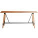 A Lancaster Table & Seating bar height wooden table with metal legs.