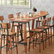 A Lancaster Table & Seating bar height trestle table with chairs and wine glasses.