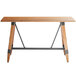 A Lancaster Table & Seating bar height wooden table with metal legs.