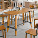 A Lancaster Table & Seating solid wood live edge bar height table with a honey maple finish.