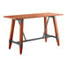 A Lancaster Table & Seating bar height wooden table with a metal trestle base.