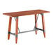 A Lancaster Table & Seating bar height wooden table with metal trestle legs and a wooden top.