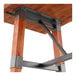 A bar height trestle base table with a solid wood live edge top and rustic mahogany finish, featuring metal supports and accents.