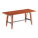 A rectangular solid wood table with a rustic mahogany finish and a metal trestle base.