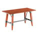 A rectangular solid wood table with a live edge and trestle base, featuring a rustic mahogany finish and metal supports.