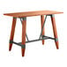 A Lancaster Table & Seating bar height trestle base table with a live edge wooden top and metal legs.