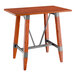 A Lancaster Table & Seating bar height wooden table with a live edge wood top and trestle base.