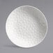 A white porcelain deep coupe plate with a textured surface.