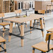 A rectangular solid wood table with a bleached oak finish and a black metal trestle base, surrounded by matching chairs in a modern dining area.