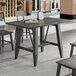 A rectangular solid wood table with a live edge and trestle base, finished in slate gray.