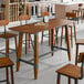 A Lancaster Table & Seating Industrial live edge bar height table with a rustic walnut finish.