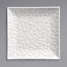 A white square plate with a textured surface and triangular pattern.