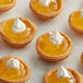 a group of small pies with yellow jelly and whipped cream