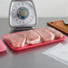 A tray of raw meat on a pink foam CKF Rose Meat Tray on a counter.