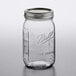 A Ball wide mouth glass canning jar with a metal lid on a table.