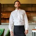 A man wearing a Henry Segal white long sleeve dress shirt and a black apron.