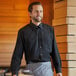 A man wearing a Henry Segal black long sleeve dress shirt serving food on a wooden board.