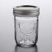 A Ball clear glass canning jar with a silver metal lid on a table.