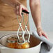 A woman using a Fox Run Canning Jar Lifter to hold a jar of peaches.