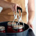 A woman using a Ball Secure-Grip Jar Lifter to pick up a jar.
