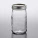 A Ball clear glass quart canning jar with a silver metal lid on a table.