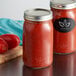 Two Ball wide mouth glass canning jars filled with red sauce on a table.