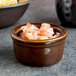 A Tuxton caramel ramekin of salsa on a table next to a bowl of chips.