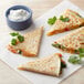 A Mission flour tortilla quesadilla with a leafy green garnish served with white sauce.