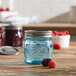 A Ball aqua blue glass jar with a silver lid filled with berries on a wooden surface.
