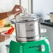 A stainless steel food processor bowl with a clear lid and green base, labeled Avamix Revolution.