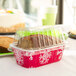 A clear plastic container holding a foil-wrapped loaf of bread.