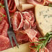 Fontana Ermes boneless Italian prosciutto on a cutting board with cheese and meat.