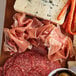 A cutting board with Tanara Giancarlo Prosciutto, cheese, and olives.