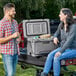 A man and woman sitting on the back of a truck with a CaterGator outdoor cooler.