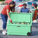 A woman opening a CaterGator Seafoam outdoor cooler to put a can inside.