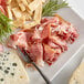 A plate with Fontana Ermes Thin Sliced Italian Prosciutto and cheese next to a fork.