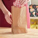 A hand holding a Choice Natural Kraft waxed paper bag.