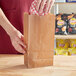 A person putting food in a Choice natural kraft waxed paper bag.