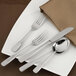 A white plate with a Walco stainless steel salad fork on a napkin.