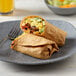 A plate with a burrito and a fork.