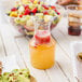 A Fineline 7.5 oz. mini carafe filled with orange juice next to a bowl of fruit.