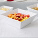 An American Metalcraft white square melamine bowl filled with fruit.