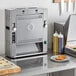 A Prince Castle vertical contact bun toaster on a counter in a professional kitchen.