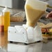 A person pouring a yellow liquid into a container on a counter.