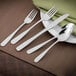 A Walco Olde Towne stainless steel bouillon spoon and a fork on a plate.