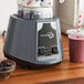 An AvaMix commercial blender filled with blackberries and other fruit.