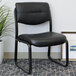 A black Boss LeatherPlus side chair next to a plant.