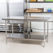 An Advance Tabco stainless steel work table with undershelf in a professional kitchen.