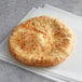 A round white pita pocket bread on white paper.