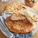 Two pieces of Father Sam's Bakery white pita pocket bread on a plate on a table.